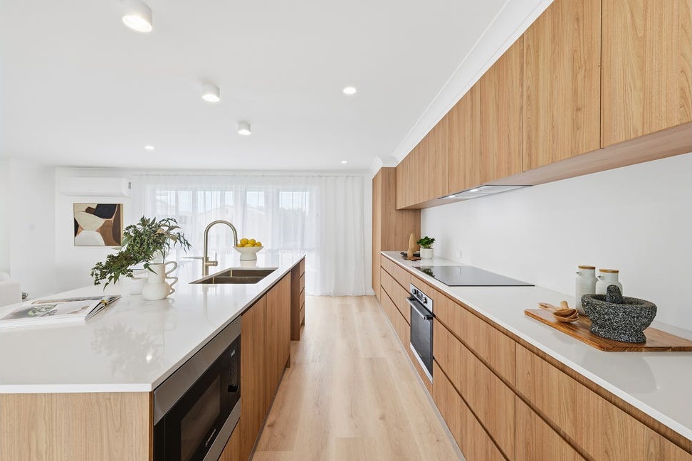 Completed kitchen with island sink, brass tap and timber cabinetry